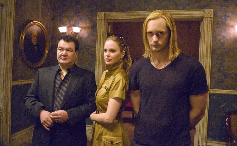 Alexander Skarsgard, Kristin Bauer van Straten, and Patrick Gallagher posing next to each other in a creepy hallway 