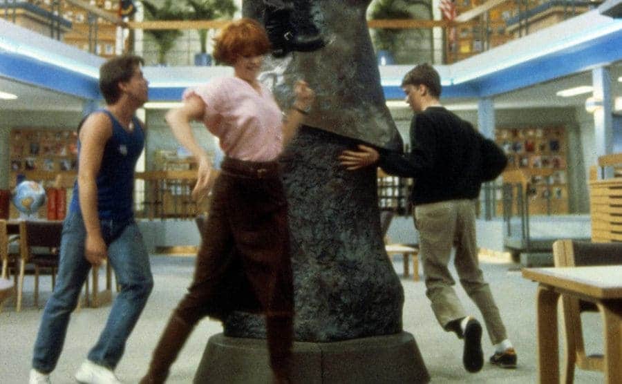 Molly Ringwald and the other guys dancing around the statue in the library 