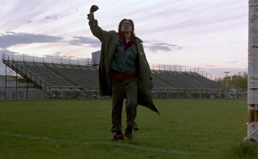 Judd Nelson with his first in the air walking off of the high school football field 
