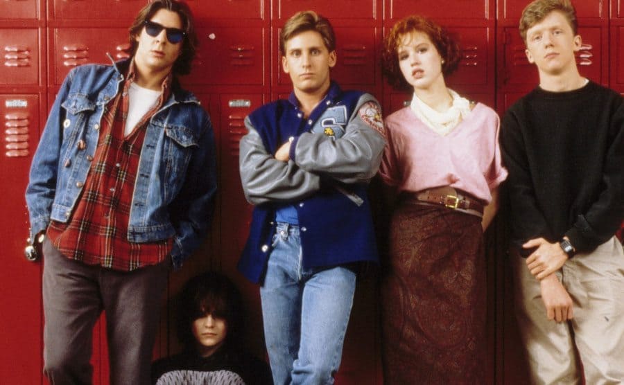 The cast of the Breakfast Club leaning against red lockers 