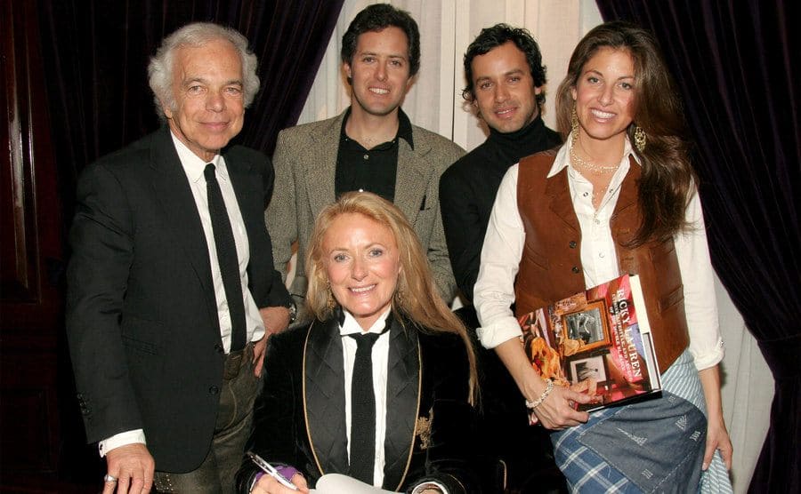 Ralph Lauren with wife, sons, and daughter standing around a desk 