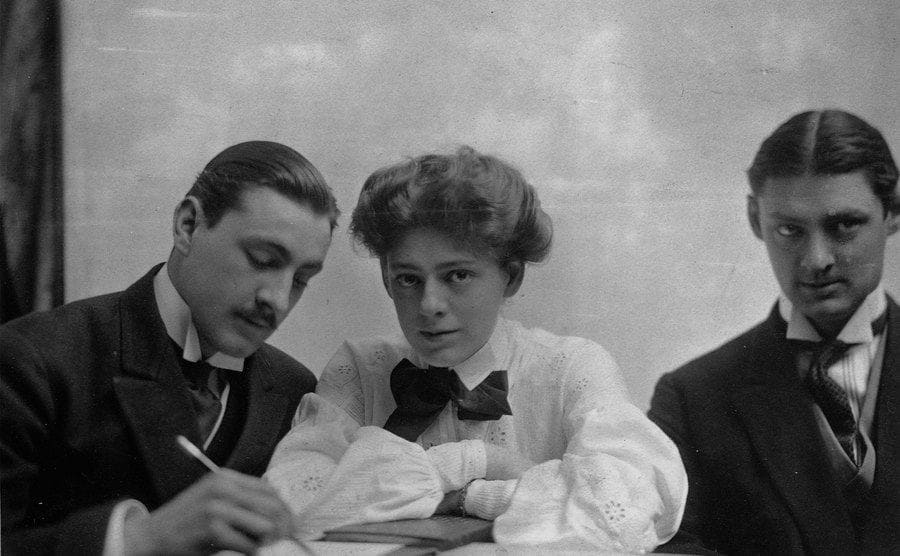 A portrait of John, Ethel, and Lionel sitting behind a desk 