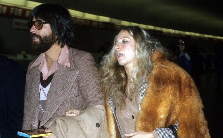 Jon Peters and Barbra Streisand walking linking arms in the airport 