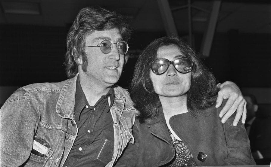 John Lennon and Yoko Ono sitting at a table at Heathrow airport 