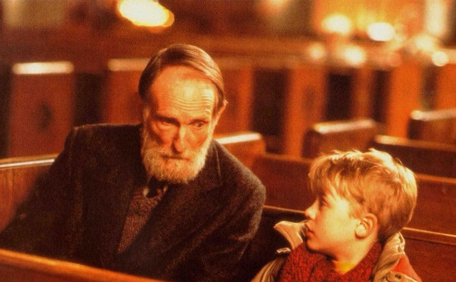 Roberts Blossom as Marley sitting in a Church pew with Macaulay Culkin in Home Alone 