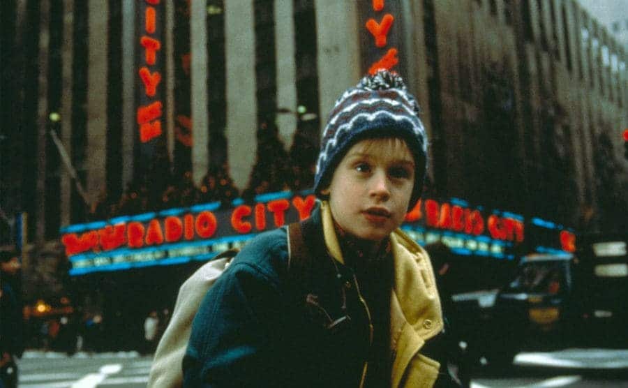 Macaulay Culkin standing in front of Radio City Music Hall in a scene from Home Alone 2