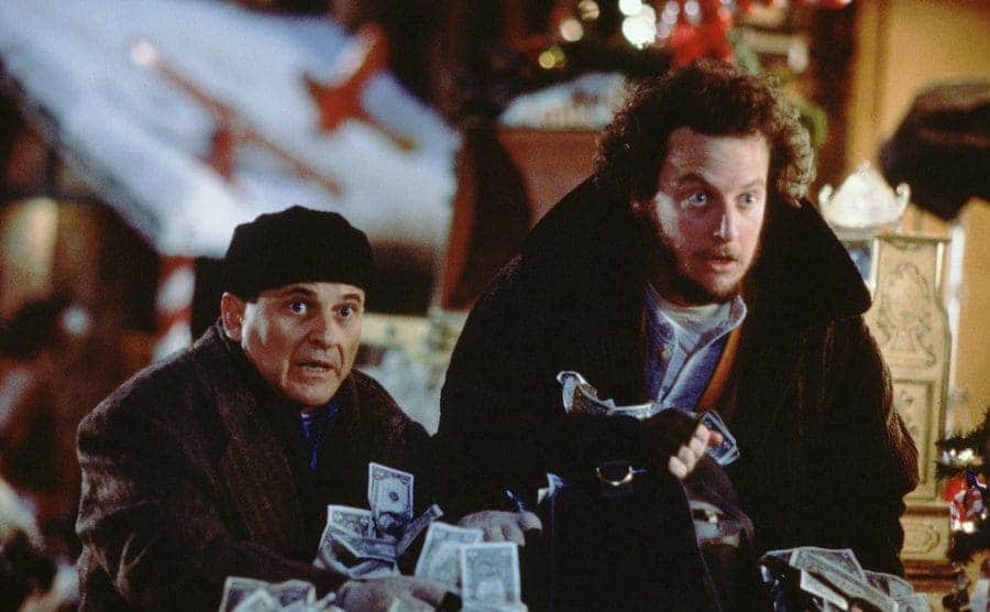 Jon Pesci and Daniel Stern with a lot of money sitting on a counter in front of them 