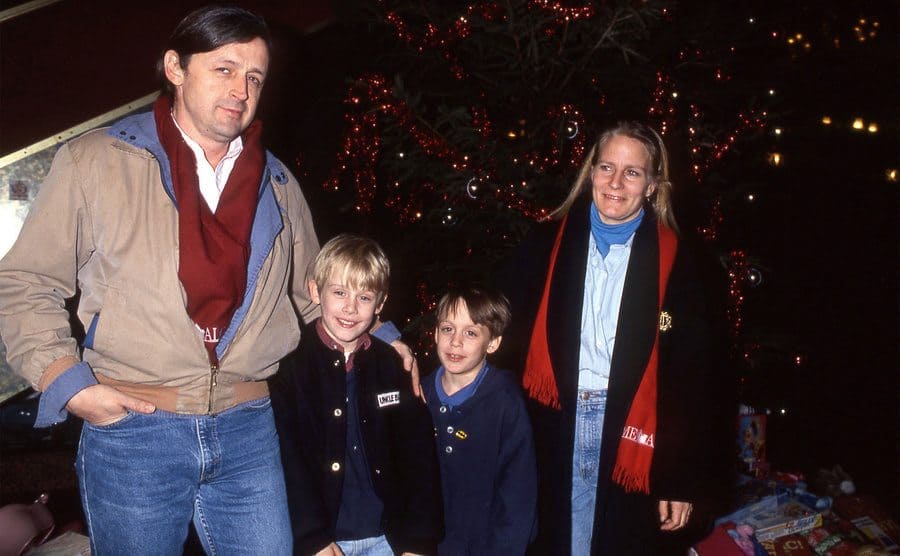 Macaulay and Kieran Culkin with their parents walking through a Christmas scene lit up 