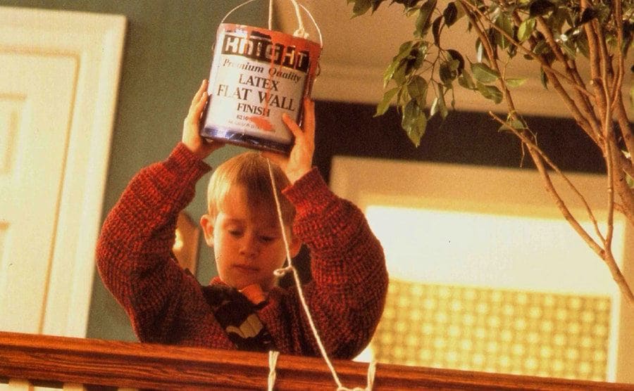 Macaulay Culkin holding a can of paint on a string about to let it drop on the burglars 