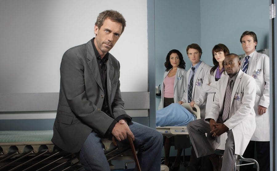 House standing separately from the rest of the cast in a hospital setting, promotional photograph. 