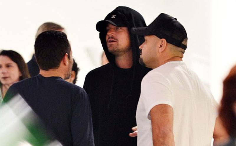 Leonardo DiCaprio, 45, kept a low profile in a baseball cap and black hoodie while talking to friends.