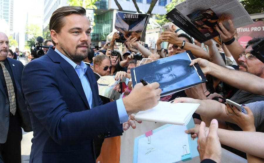 Leonardo DiCaprio signs autographs for fans on the red carpet.