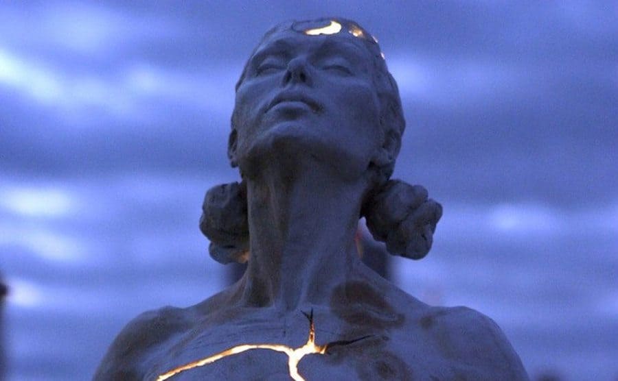 The head and shoulders of a female sculpture with cracks of light coming through 