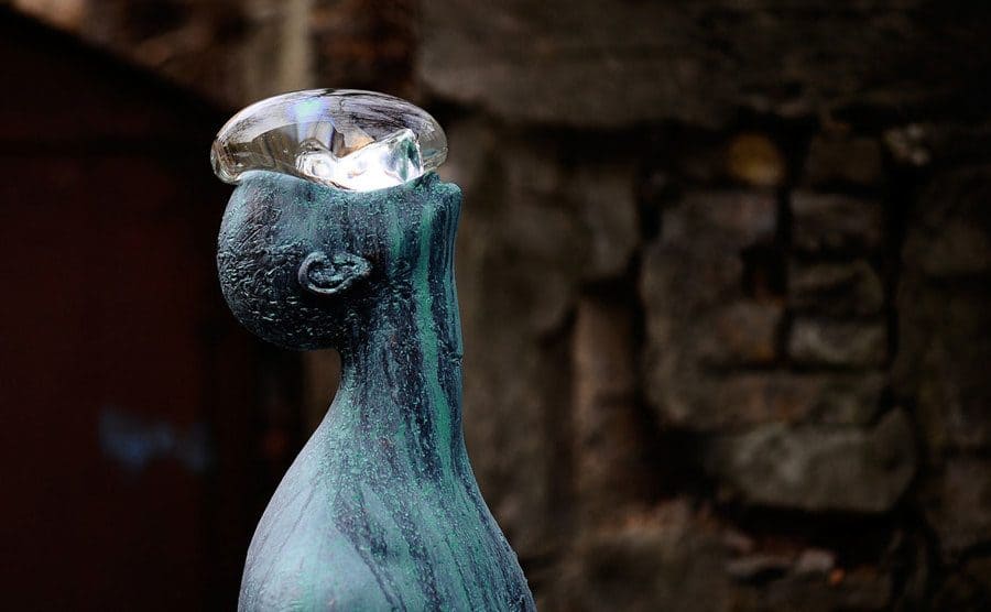 The large glass raindrop on the bronze statue of a man 