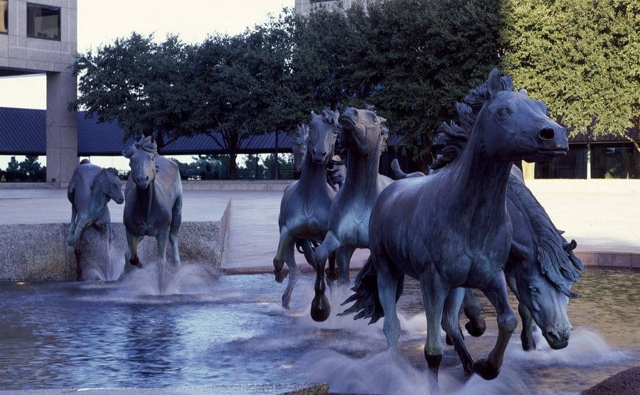 Mustang sculptures running through a fountain 