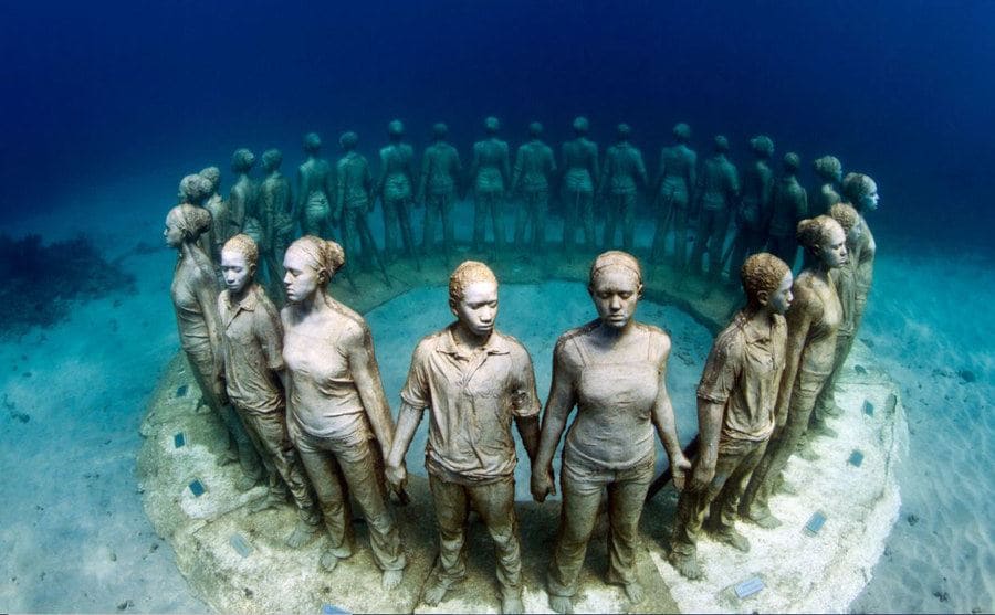 The sculpture of people standing in a circle holding hands with their backs to each other 