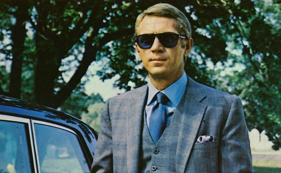Steve McQueen walking past a car in a scene from The Thomas Crown Affair 