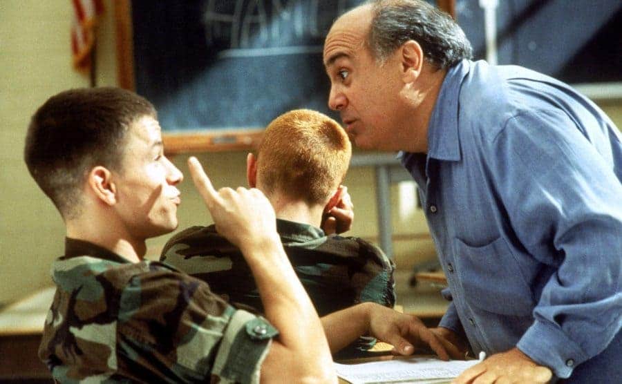 Danny DeVito looking angry standing over Mark Wahlberg’s desk while he is in uniform 