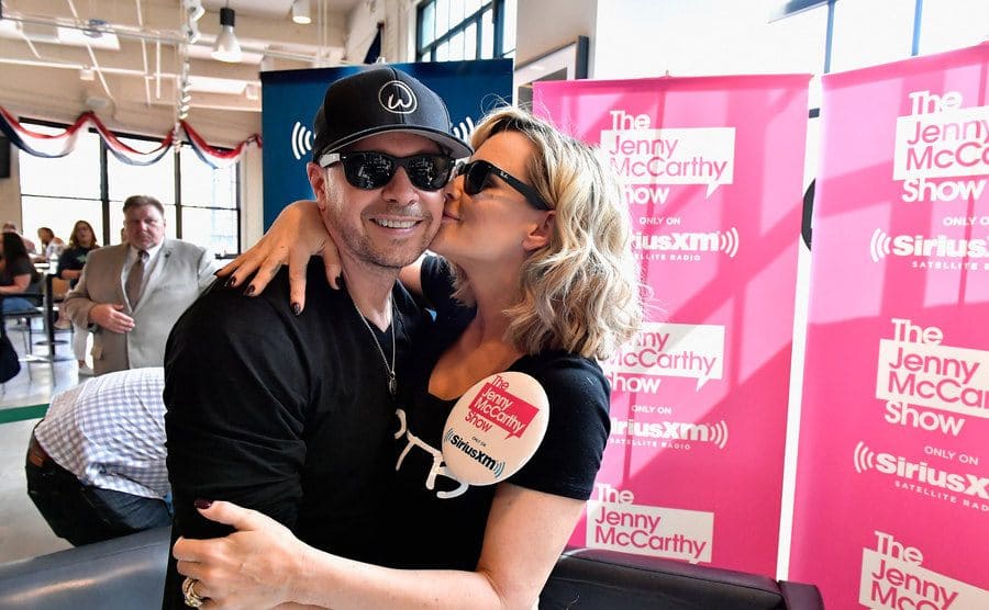 Donnie Wahlberg and Jenny McCarthy posing on the set of Jenny McCarthy’s radio show 