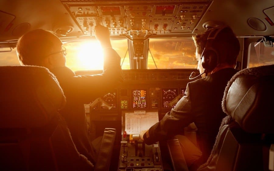 Caucasian pilots flying a jet at sunset