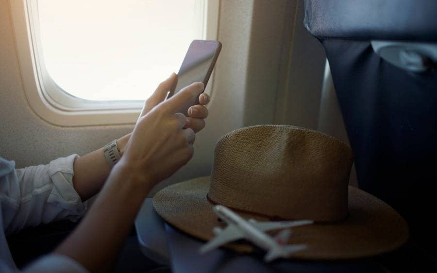 travelers use cellphone near window seats on the airplane.