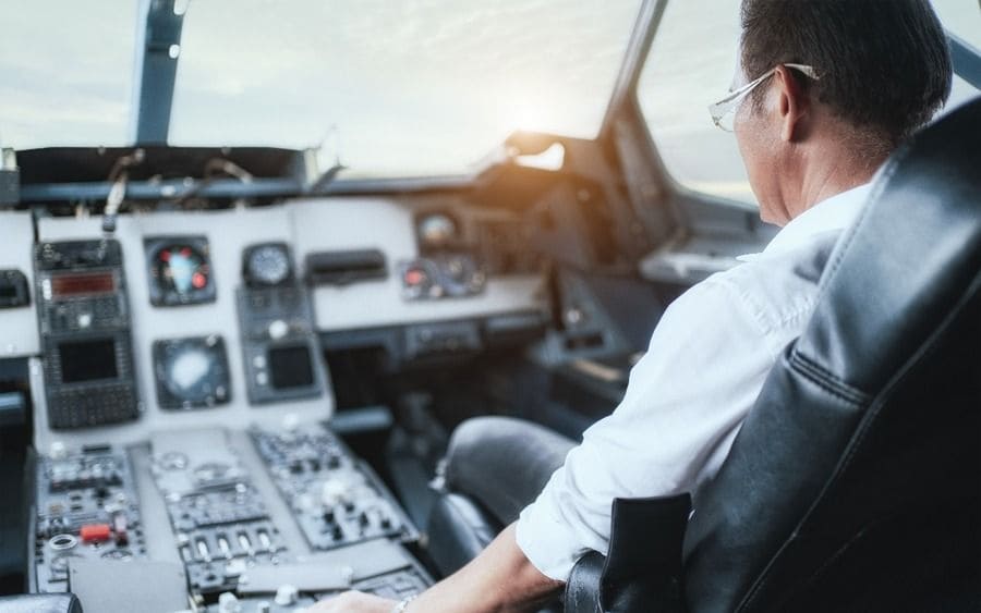 Male pilot sitting in an airplane cabin flying.