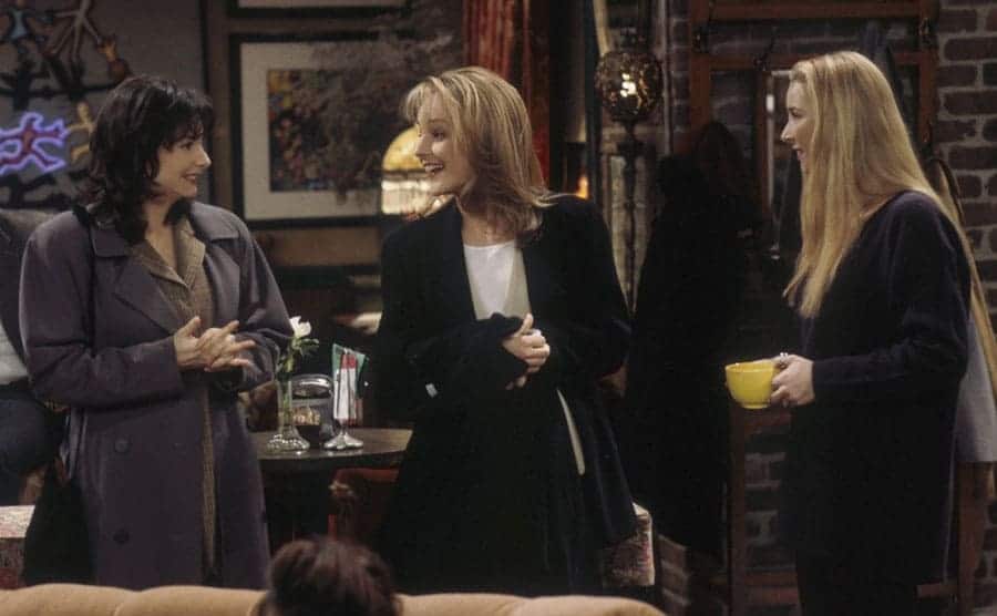 Leila Kenzle, Helen Hunt, and Lisa Kudrow standing around the coffee shop in a scene from Friends