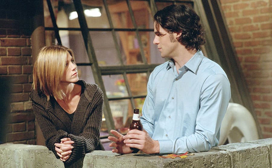 Jennifer Aniston and Eddie Cahill standing on her porch in a scene from Friends 
