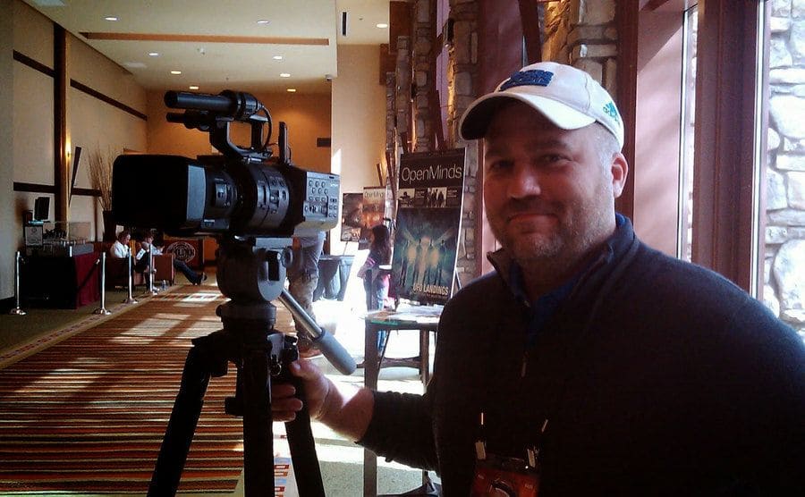 Adam Dew is standing beside his film camera.