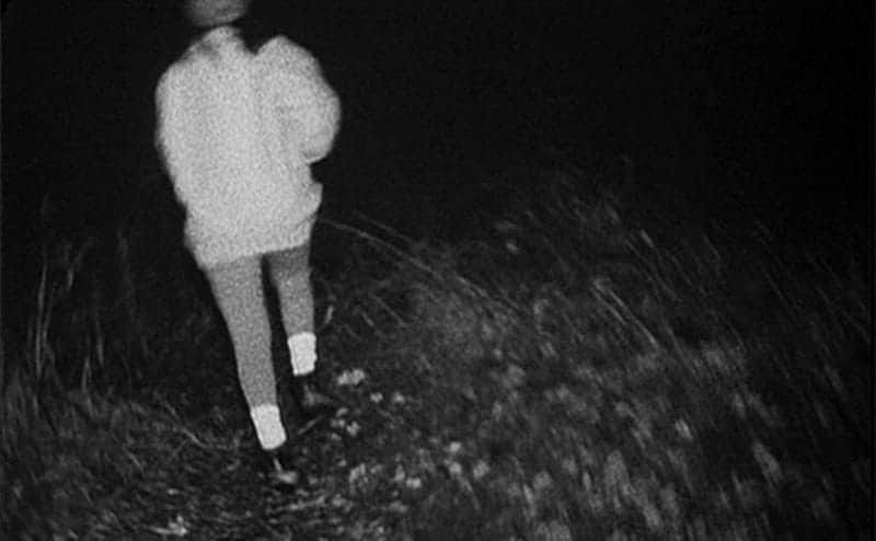 A still from the movie in which a girl is running through the woods.