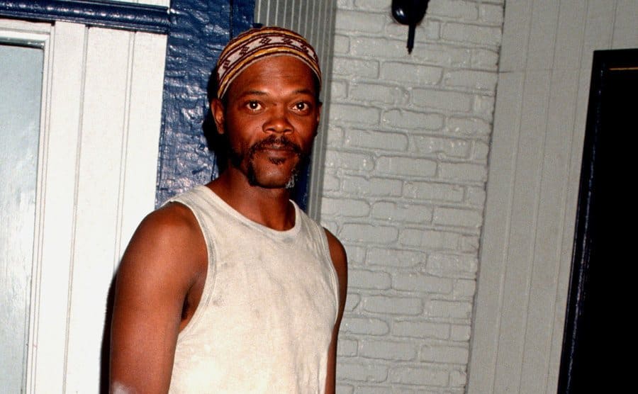 Samuel L Jackson standing in an apartment with white brick walls 