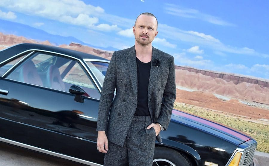 Aaron Paul standing in front of a black car at the El Camino film premiere 