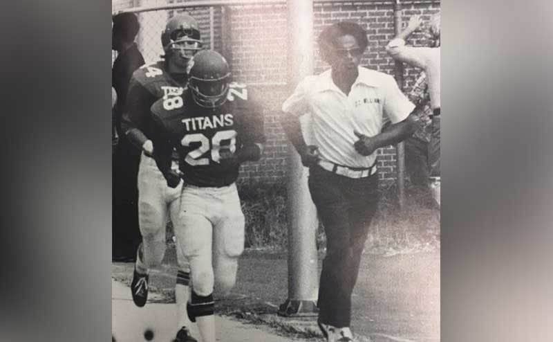 Coach Boon running alongside his players at a game. 