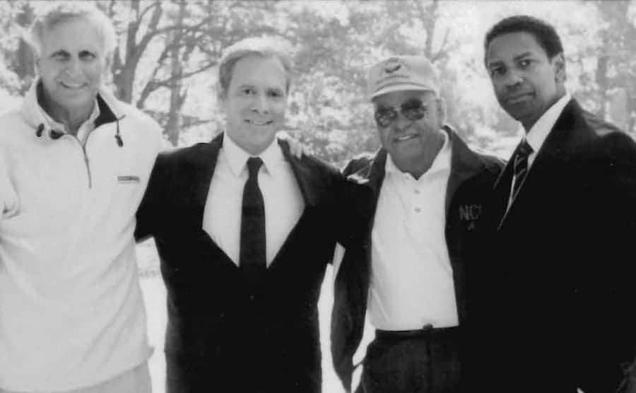 Former T.C. Williams assistant coach Bill Yoast, coach Herman Boone posing for a photo along with Will Paton and Denzel Washington. 