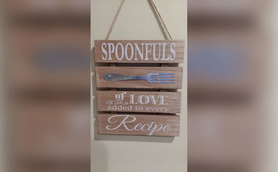 A sign that says, ‘spoonfuls of love added to every recipe’ and on said sign there is a fork picture. 
