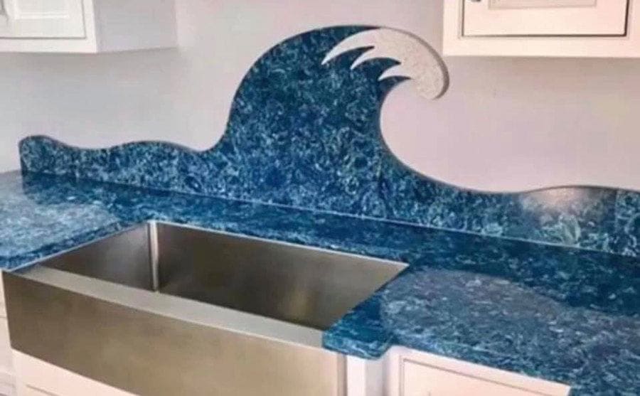 A blue epoxy countertop that crawls up the wall to make the shape of a wave across the wall 