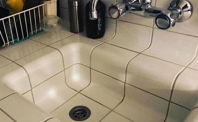 A kitchen sink that continues the countertop tiles to create some kind of optical trickery. 