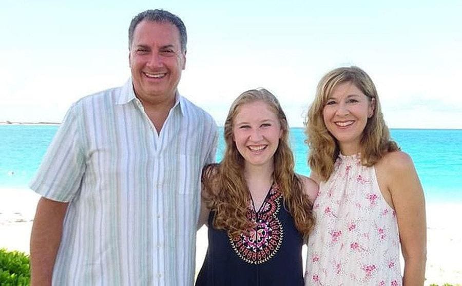 Rebecca Cartellone posing with her arms around her parents Joseph and Jennifer Cartellone on the beach. 