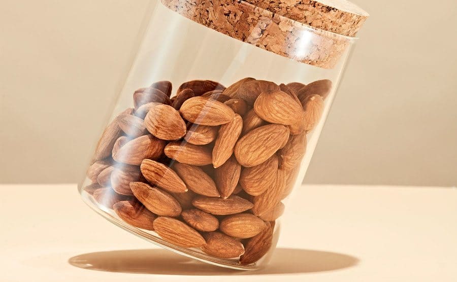 A jar of almonds tilting to the side. 