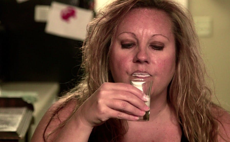 Heather drinking white paint out of a shot glass. 