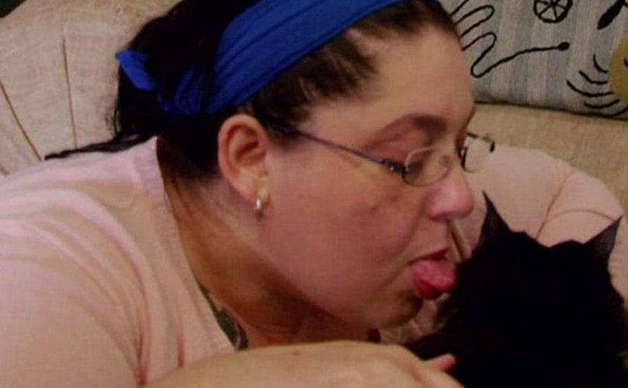A woman is seen licking her cat with the intent to eat the fur. 