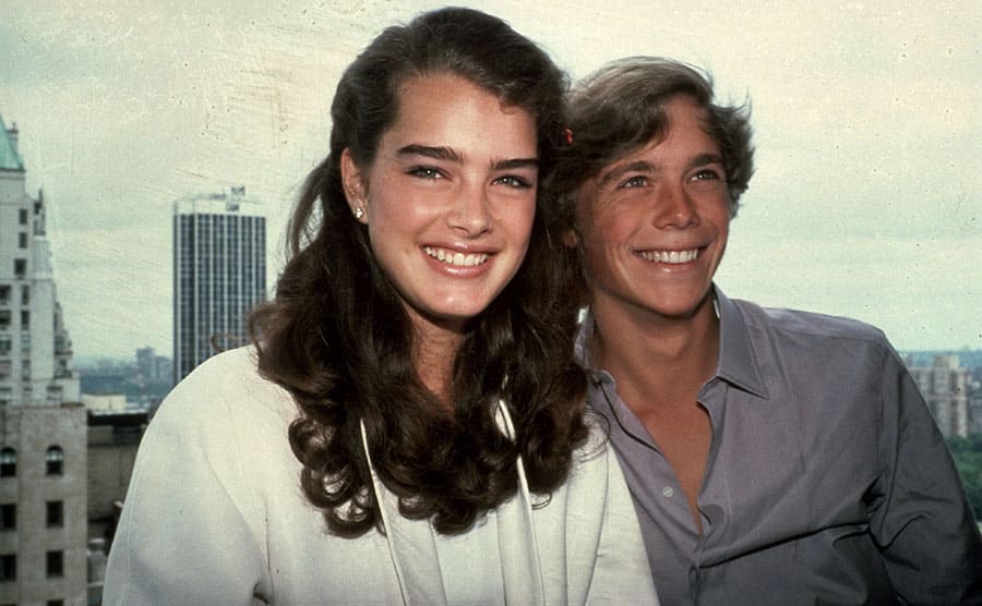 Brooke Shields and Christopher Atkins posing in front of a skyline view of New York 