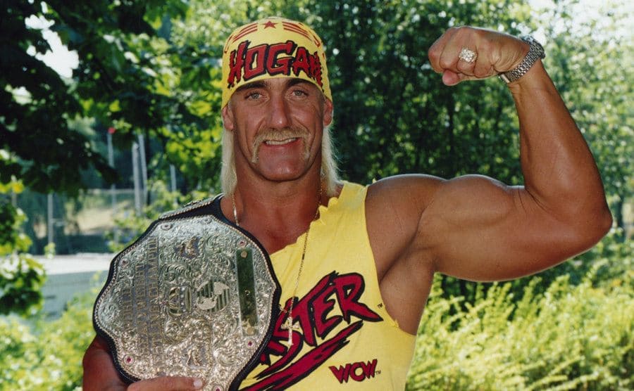 Hulk Hogan flexing one arm while holding his championship belt in the other 