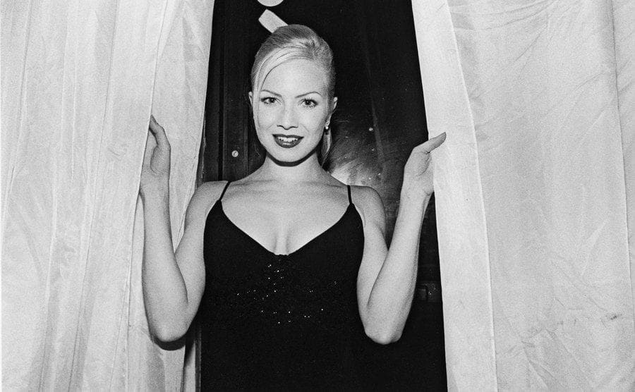 Traci Lords posing emerging from behind curtains 