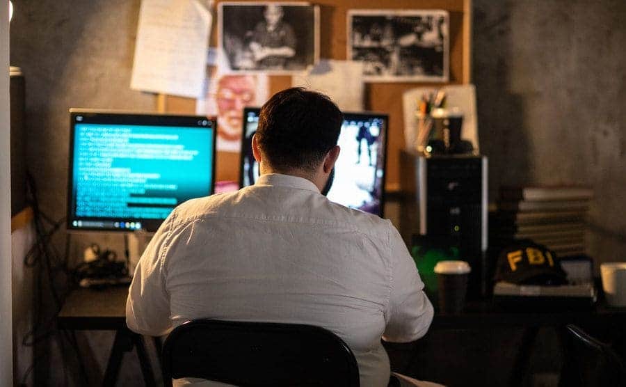 Overweight man using a computer late at night at the office.