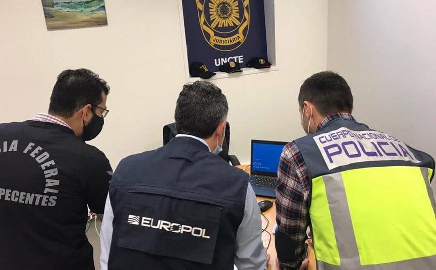 Europol and other police officers look over the information on a computer. 