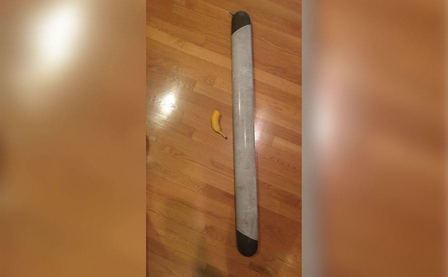A large Tube shaped item on the floor with half a banana placed next to it for scale. 