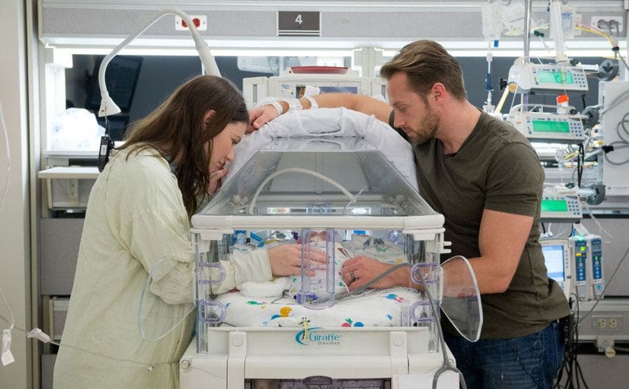Danielle and Adam are standing in the NICU by the quintuplet’s incubator. 
