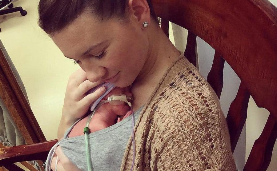 Danielle is holding her newborn daughter close to her chest. 