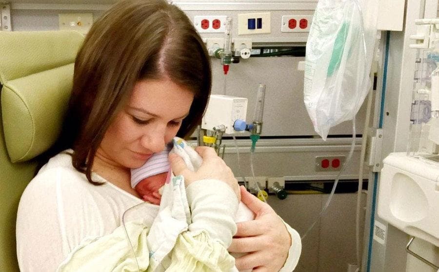 Danielle Busby is holding her newborn daughter to her chest in her hospital room. 
